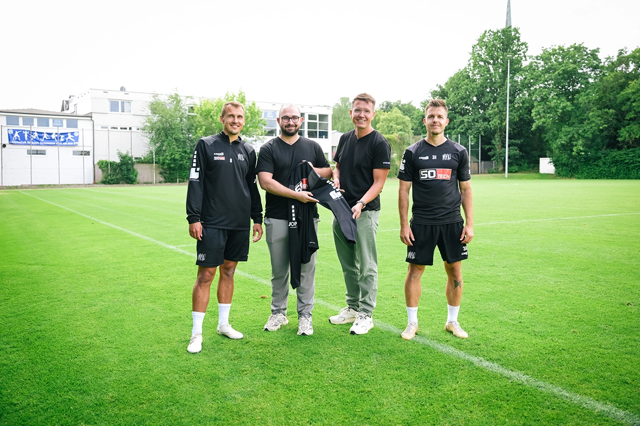 Vertreter von STROHBECKE übergeben Trainingskleidung an Spieler des VfL Osnabrück auf dem Trainingsplatz.