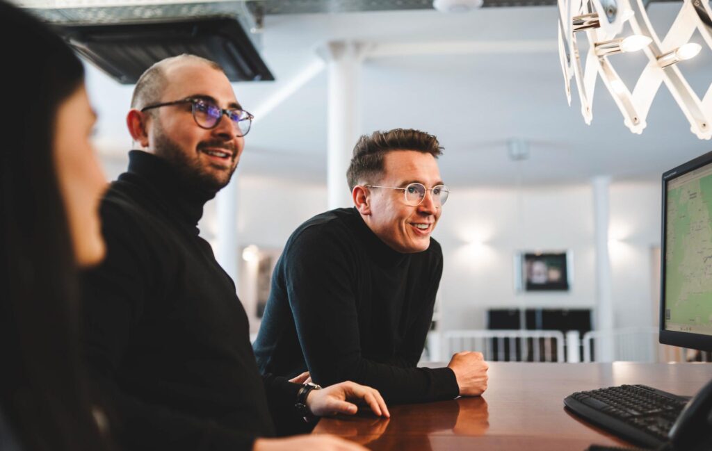 Drei Mitarbeitende von STROHBECKE in Herford besprechen gemeinsam eine digitale Tourenplanung am Computer – Symbol für Teamarbeit und moderne Logistik.