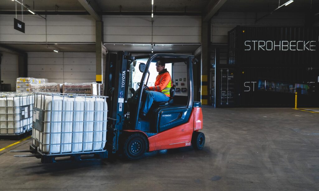 Ein Auszubildender von STROHBECKE transportiert mit einem Gabelstapler Ware in der Logistikhalle.