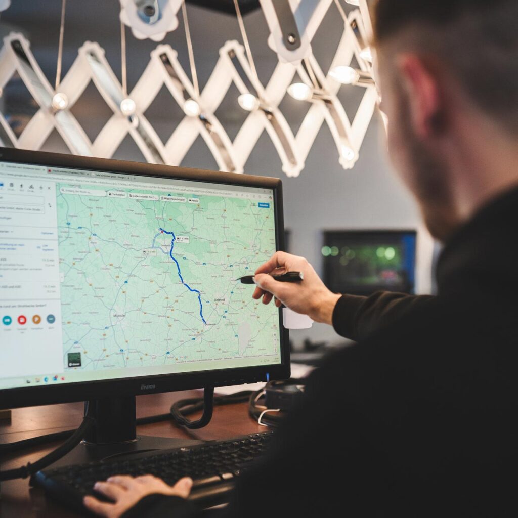 Auszubildender bei STROHBECKE plant am Computer eine Transportroute in der Logistik.