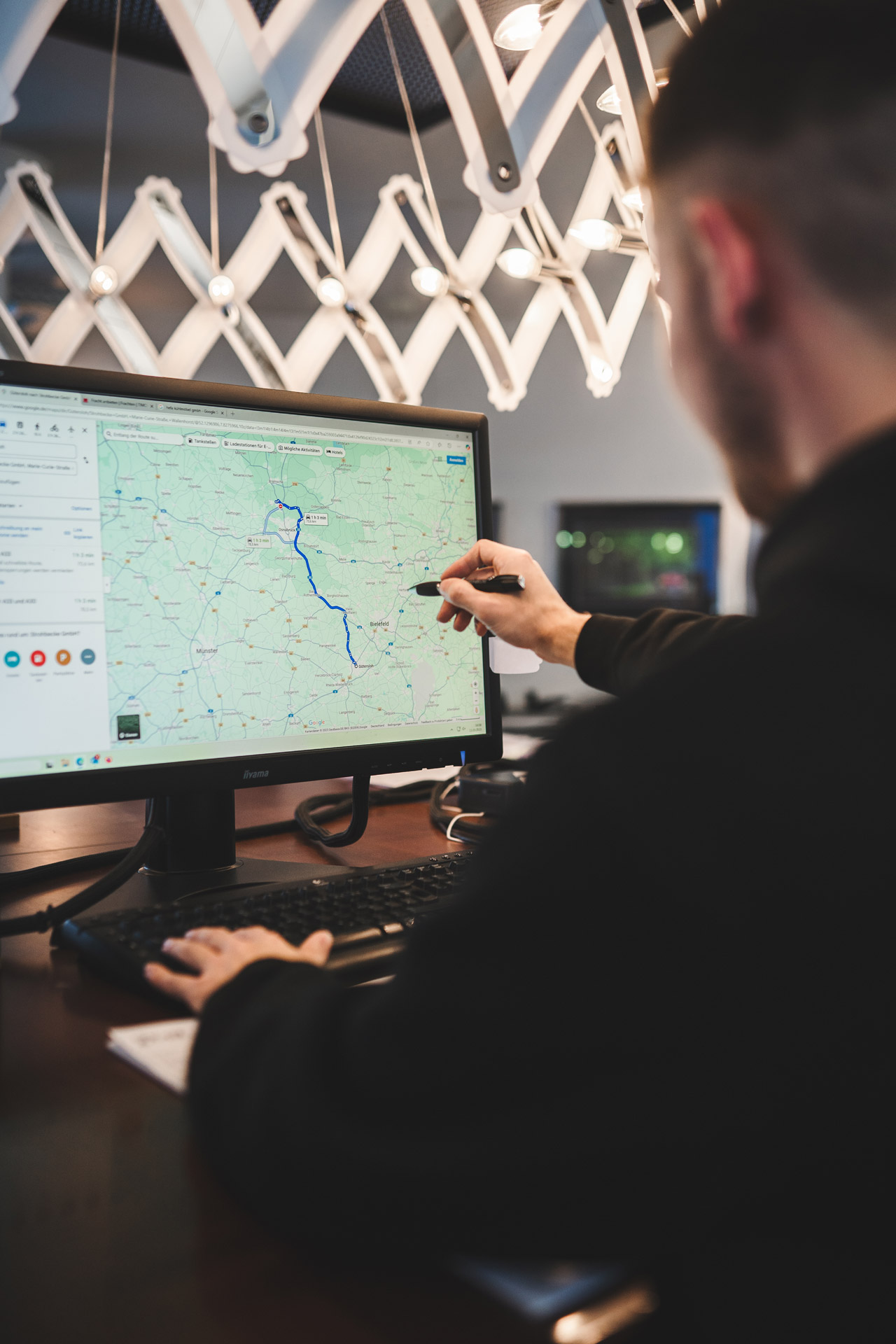 Mitarbeiter plant eine Transportroute am Computer auf einer digitalen Karte.