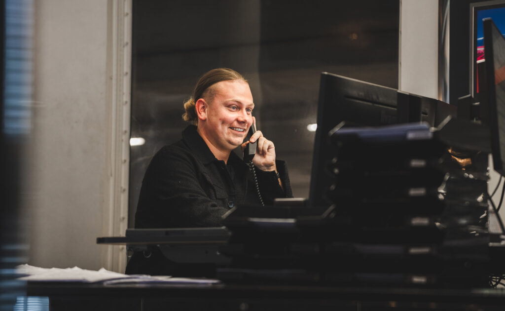Mitarbeiter telefoniert lächelnd am Arbeitsplatz im Büro.